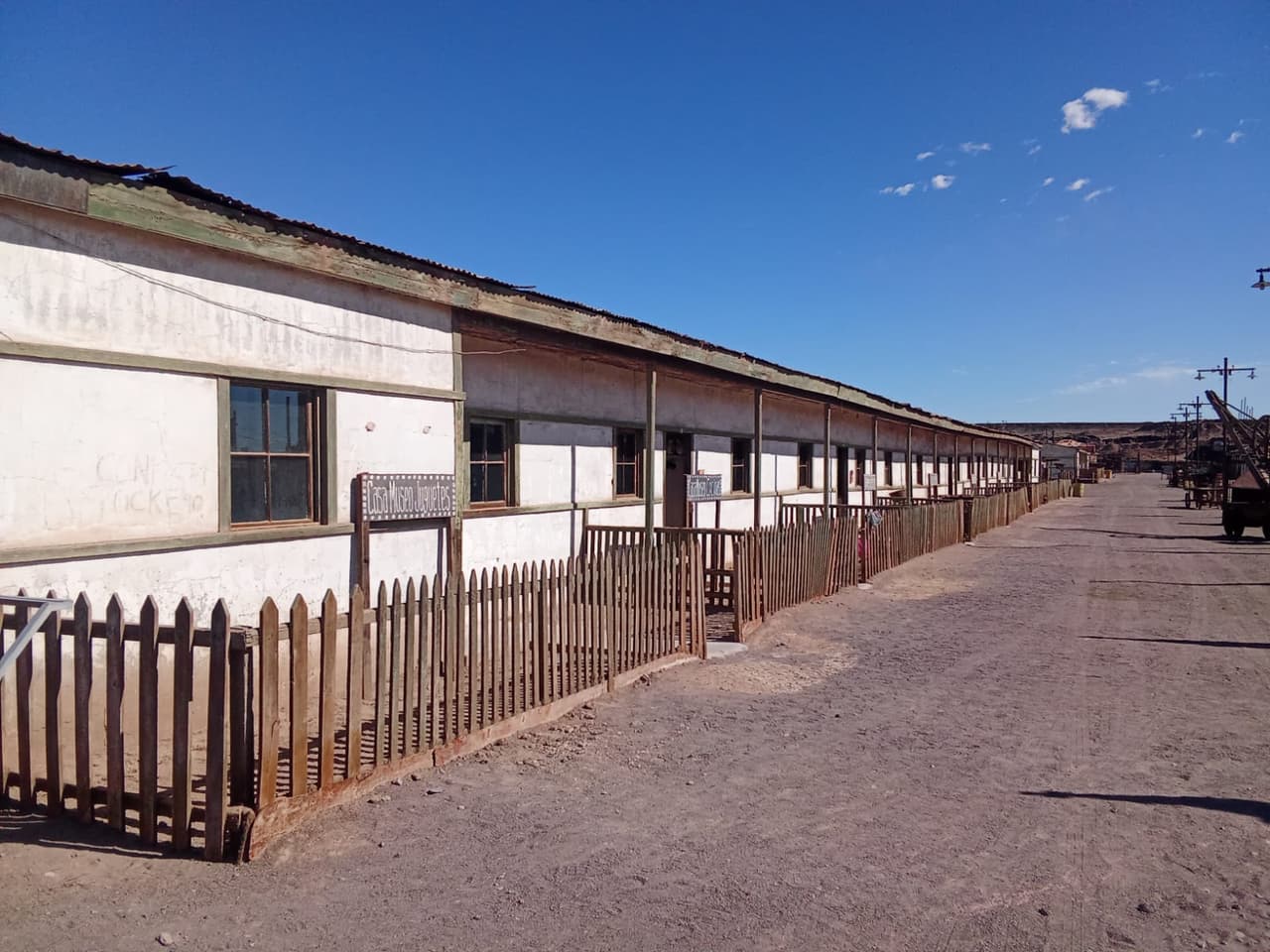 Calle de la oficina con casas de muros blancos, cerco de madera y el letrero Casa Museo Juguetes